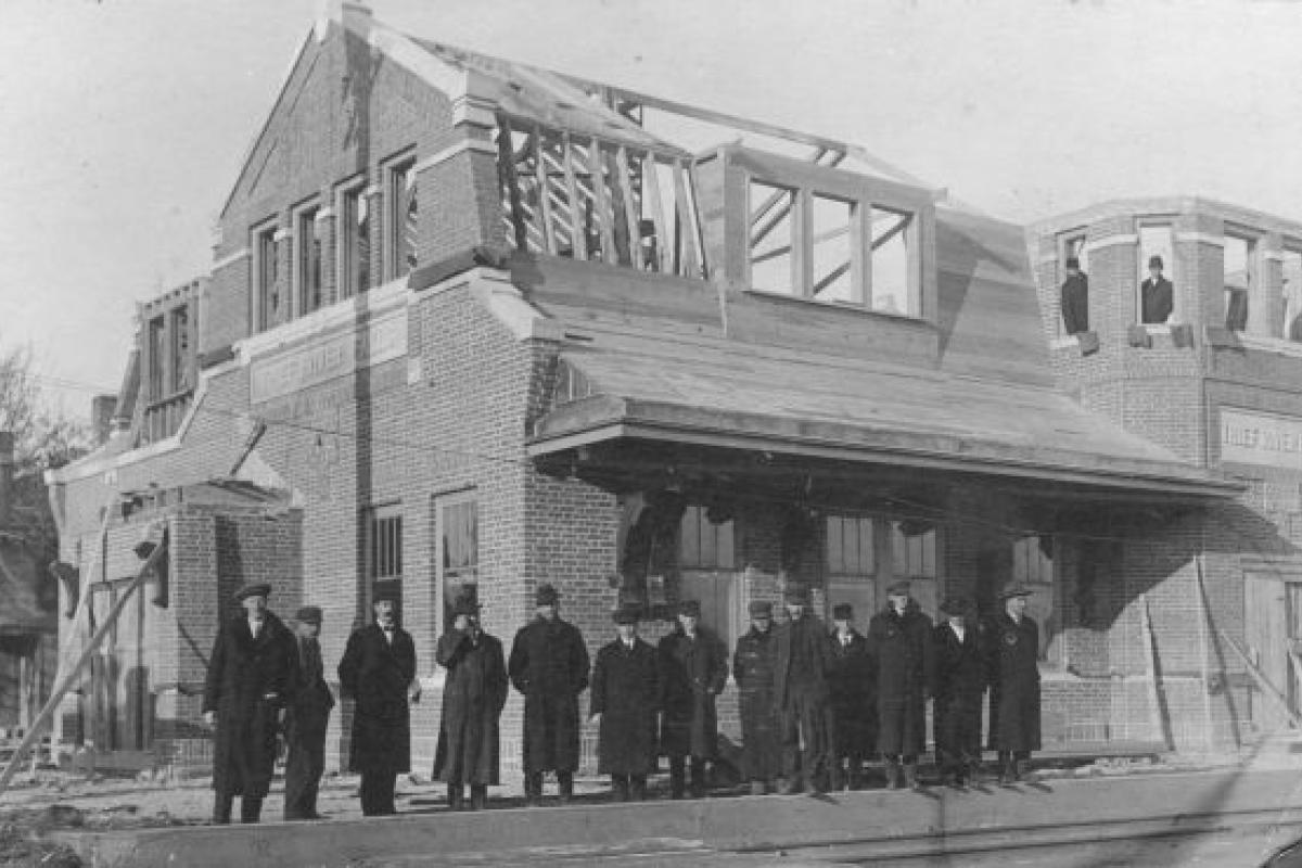 old black and white photo of people standing in front of a building 