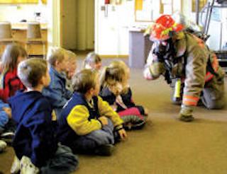 firefighter in uniform teaching a group of children